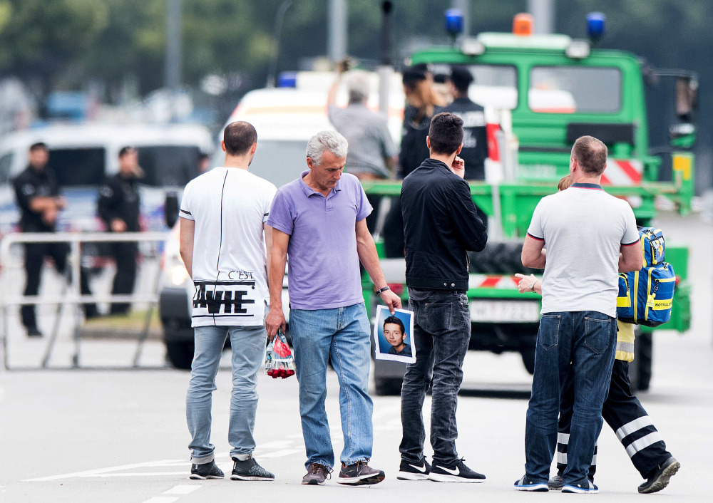 The father of a victim, center, holds a picture of his son near the Olympia shopping center where a gunman on Friday killed nine people and himself, on Saturday in Munich, Germany.