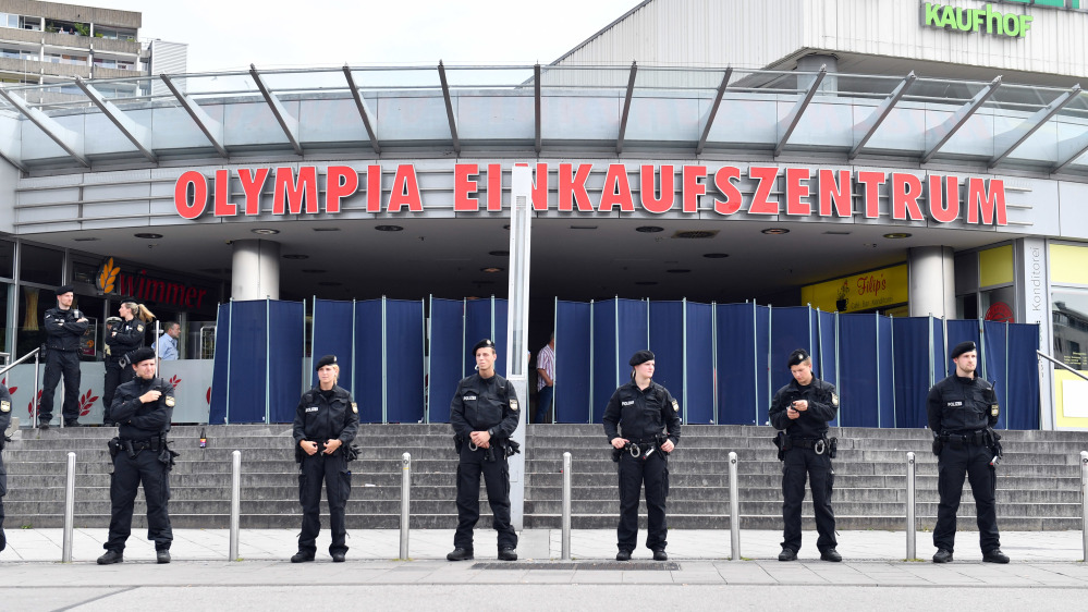 Police officers stand in front of the Olympia mall on Saturday in Munich, Germany, one day after an 18-year-old gunman opened fire at the crowded Munich shopping center and fast-food restaurant and killed nine people before killing himself.