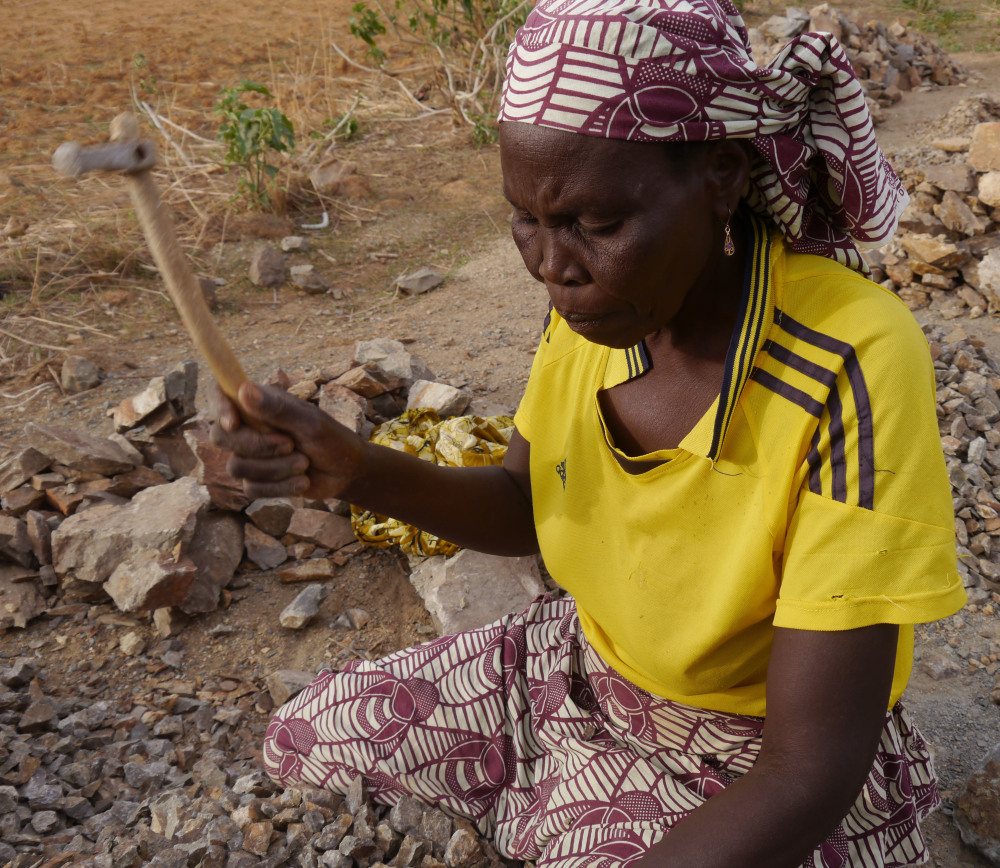A woman crushes rocks in a quarry at Maroua, Cameroon. Menaced by hunger and suicide bombers, women spend grueling days breaking rocks into gravel to earn a living.