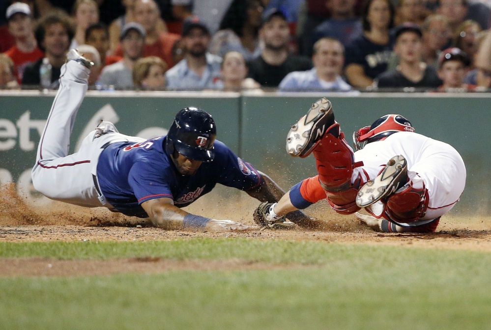 Boston catcher Sandy Leon, right, dives in an attempt to tag Minnesota's Kennys Vargas at home plate during the seventh inning of Saturday's game in Boston. Vargas was initially ruled out, but Minnesota challenged the call and it was reversed.