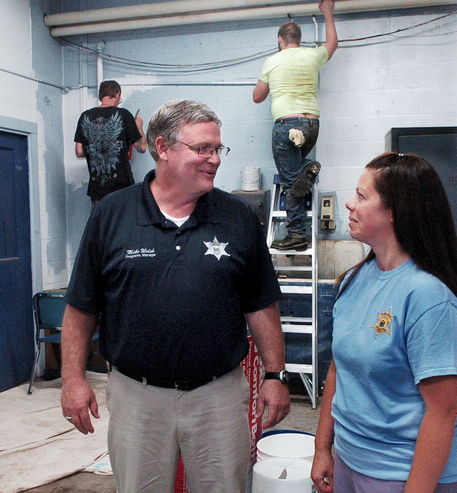 Somerset County Jail Programs Manager Mike Welch speaks with Community Corrections Program Supervisor Teresa Brown as participants in a community service program paint walls at Madison Junior High School.