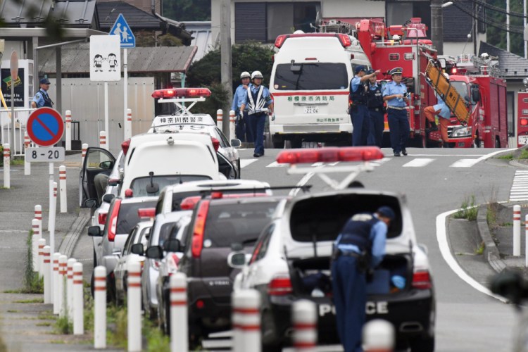 Police officers stand by with ambulances and firetrucks on a street near a facility for the handicapped where a number of people were killed and dozens injured in a knife attack Tuesday in Sagamihara, outside Tokyo.