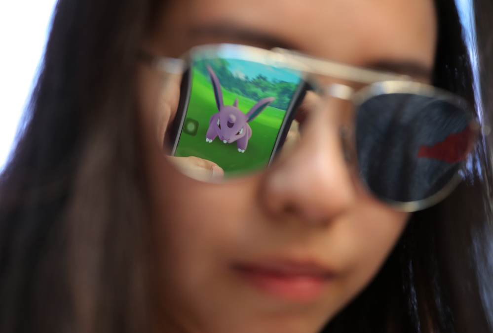 A mobile screen is reflected on a fan's sunglasses as she plays Pokemon Go in Hong Kong on Monday.