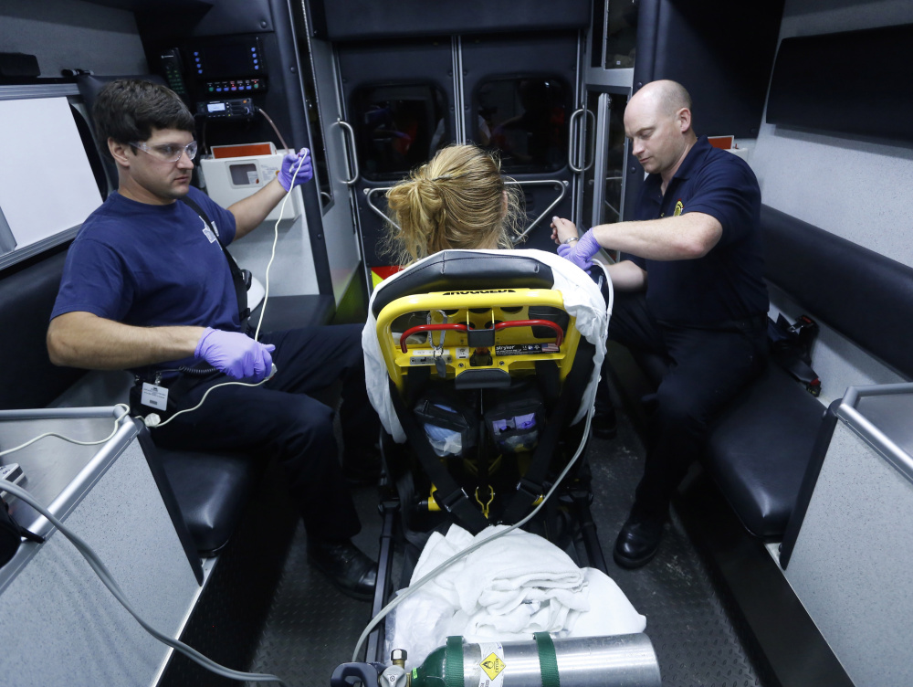 Portland paramedics Steven Bishop, left, and Nathaniel Sparling monitor a woman whom they revived Aug. 12, 2015, after she was found unconscious from a heroin overdose. Maine is the only New England state that doesn't offer some sort of immunity from prosecution for people who seek medical assistance for someone experiencing an overdose.