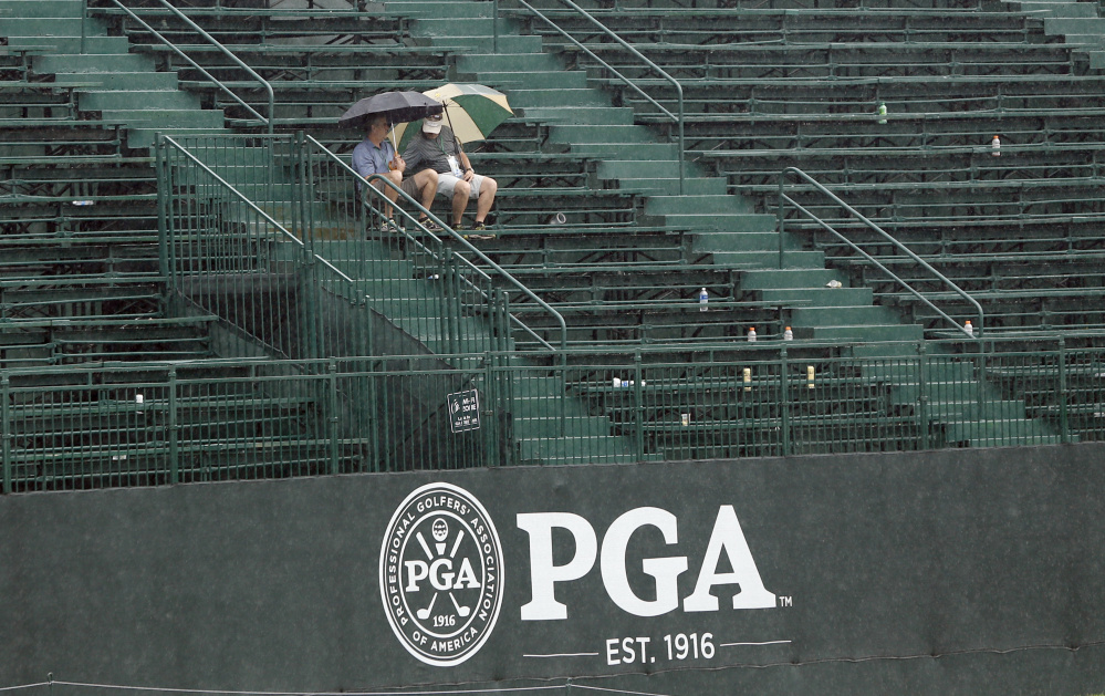 Two fans sit in the grandstand on the 18th green during a weather delay in the third round of the PGA Championship at Baltusrol Golf Club in Springfield, N.J. on Saturday.