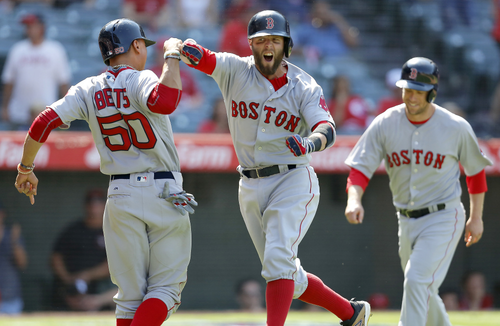 Dustin Pedroia, center, celebrates with Mookie Betts, left, after Pedroia hit a three-run home run to give Boston the lead in the ninth inning of its 5-3 win over the Los Angeles Anges in Anaheim, California.