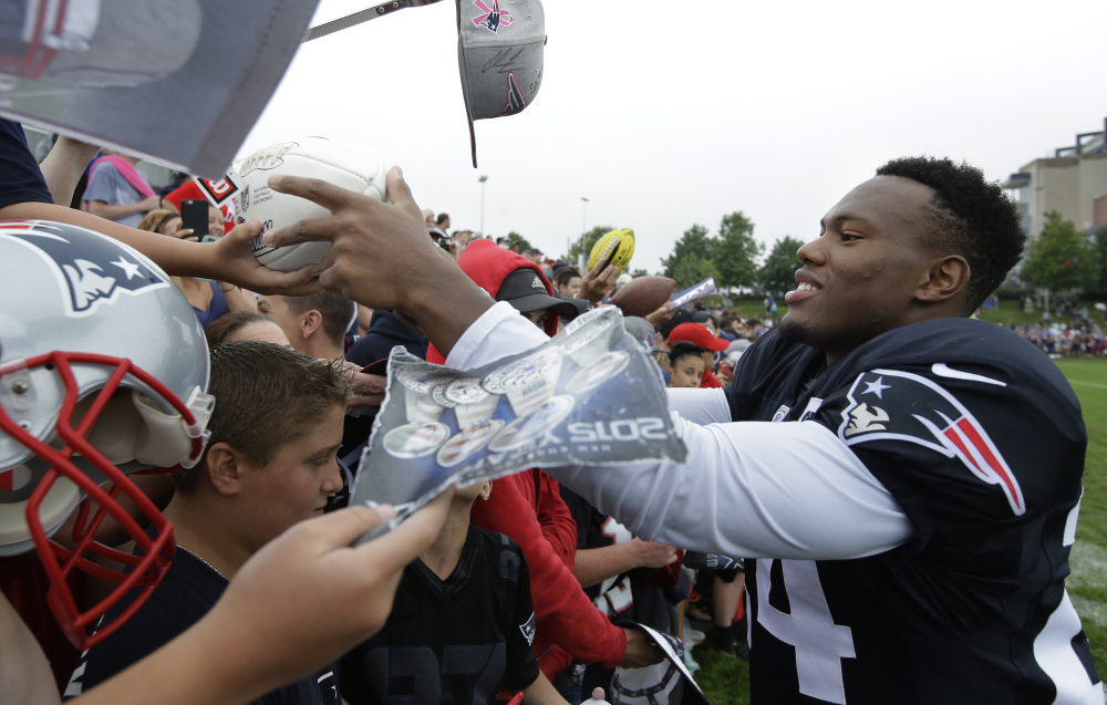 Patriots cornerback Cyrus Jones, right, signs autographs for fans after practice Sunday in Foxborough, Mass. Jones, a rookie from Alabama, has looked impressive running back punts in training camp.