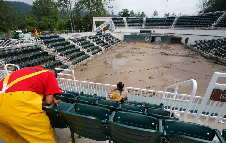 Workers clean seats on June 28 in the stands at Center Court at the Greenbrier Resort in White Sulphur Springs, W. Va. The Greenbrier’s 710-room hotel is reopening to the public more than two weeks after the property was ravaged by floods.   Associated Press/Steve Helber