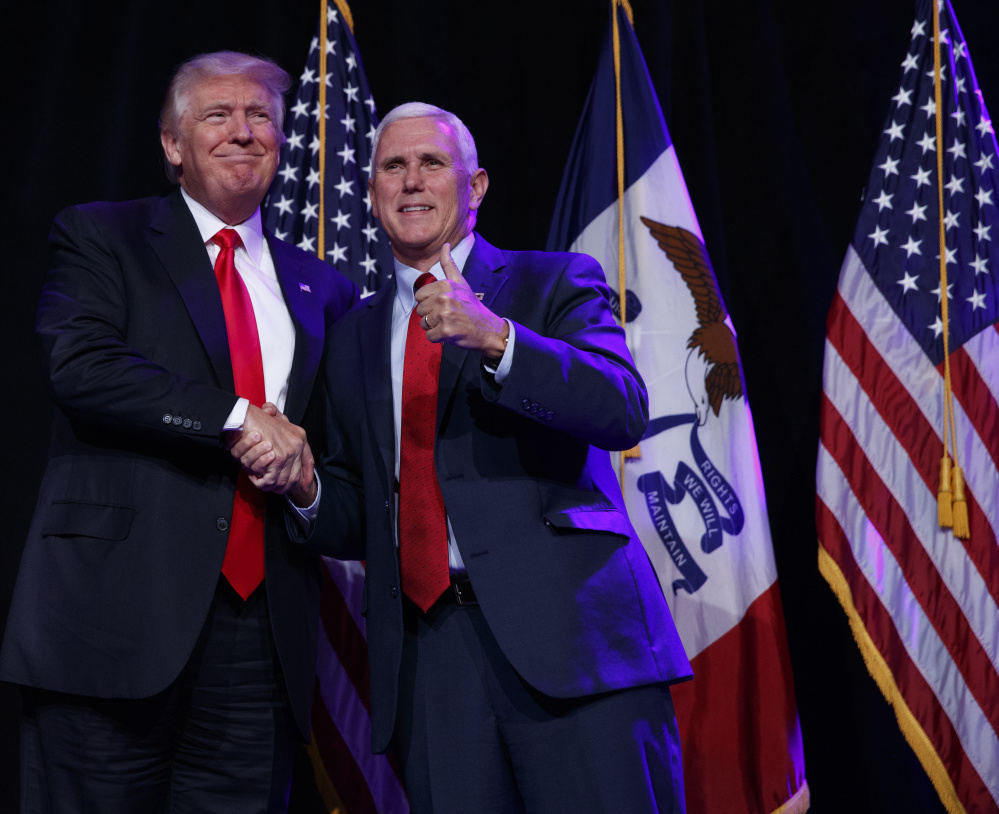 Republican presidential candidate Donald Trump shakes hands with his running mate, Indiana Gov. Mike Pence, during a campaign rally Friday in Des Moines, Iowa.