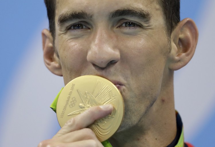 Michael Phelps kisses his gold medal after the men's 4x100-meter freestyle final during the swimming competitions at the 2016 Summer Olympics.