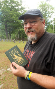 Historian Walter Skold of Freeport holds a book of poetry by once-famous poet Holman Day while visiting his grave at Nichols Cemetery in Vassalboro on Monday.
