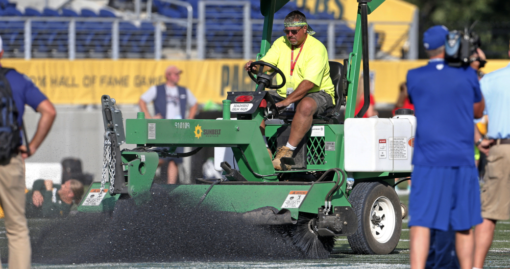A grounds crew member tries to scrape the logo off the center of the field at Tom Benson Hall of Fame Stadium in Canton, Ohio, Sunday.
