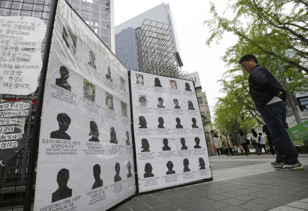Outside Samsung offices in Seoul, South Korea, a man views victims who were former factory employees of the electronics giant. More than 200 cases of serious illness have been documented and 76 people have died, most in their 20s and 30s.