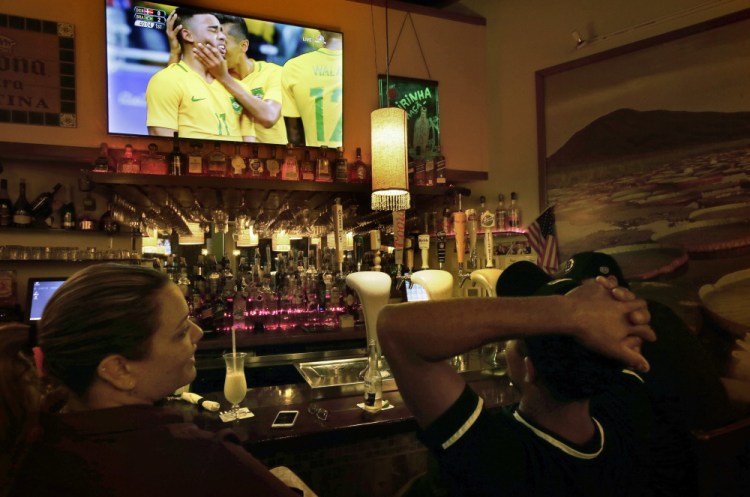 Camila Ornelas, left, and Vander Junior, right, both originally of Brazil, watch a televised soccer match between Brazil and Denmark at the Rio Olympics while sitting at the bar in the Tropical Cafe, in Framingham, Mass. There is pride of the Rio Olympics in this Boston bedroom community, nicknamed "Little Brazil" for its thriving population of Brazilian immigrants and their shops and bakeries. But there is also skepticism in Framingham, and in other major Brazilian enclaves around the U.S., among those who fled poverty and corruption.