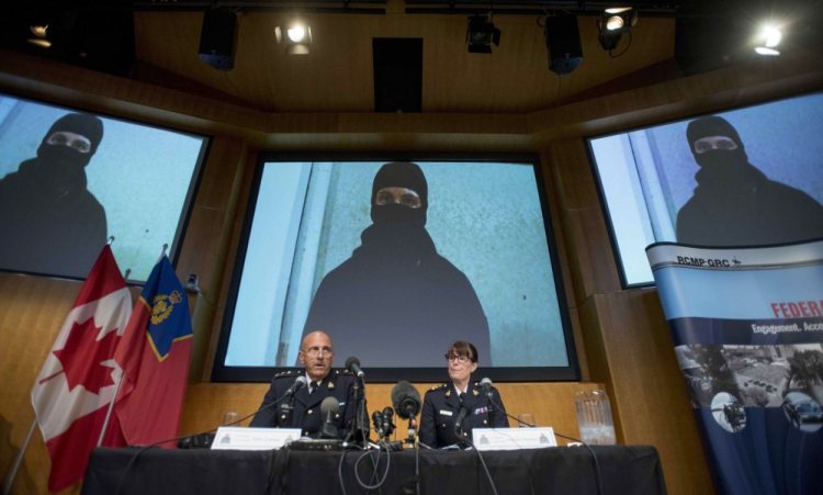 Video footage showing Aaron Driver is seen behind Royal Canadian Mounted Police Deputy Commissioner Mike Cabana, left, and Assistant Commissioner Jennifer Strachan during a news conference in Ottawa for what the RCMP are calling a terrorism incident in Strathroy, Ontario.
