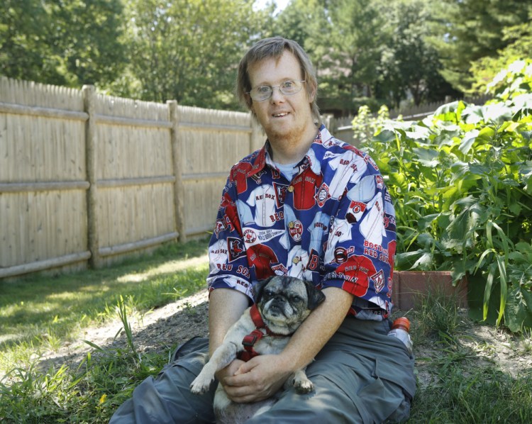 Greg Rogers, 45, poses with his dog Zambi next to his garden at his home in Portland. Rogers grows vegetables for a local food pantry and volunteers with Garbage to Garden. Joel Page/Staff Photographer