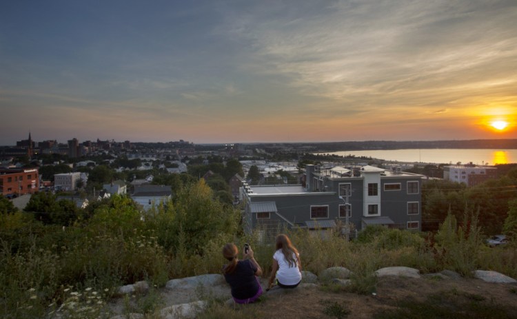 Nicole Hoglund of Portland, left, watches the sunset with her niece Sophia Lanzano of New Jersey in August from Fort Sumner Park in Portland. The top floor of a proposed condominium complex would obscure this view of Back Cove.