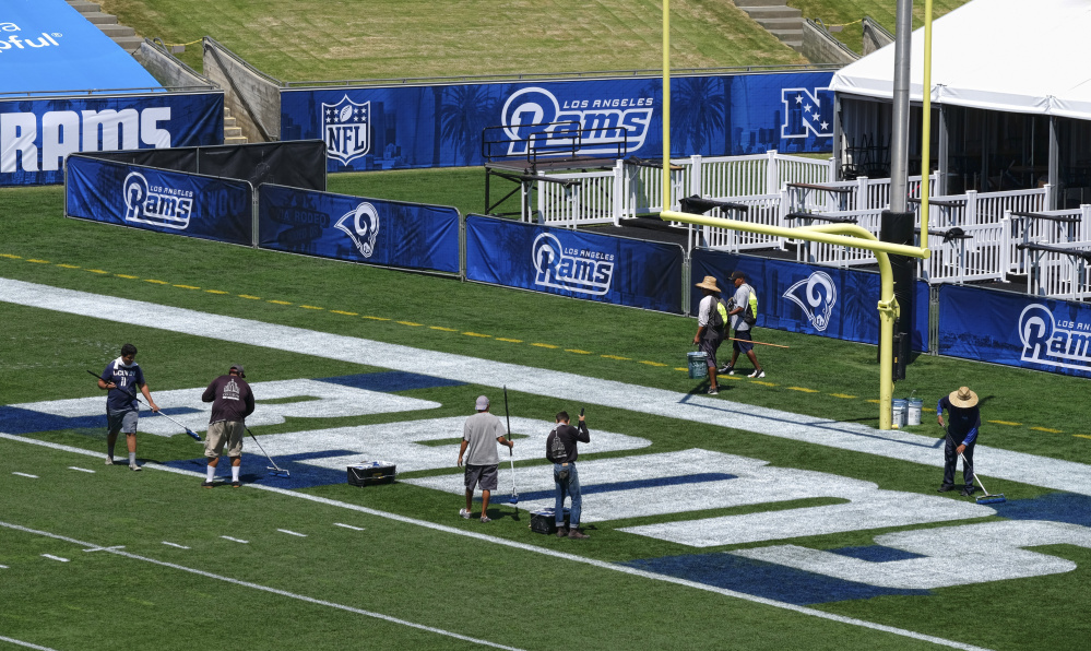 Crew members paint the end zone with the Rams lettering at the Los Angeles Memorial Coliseum – the team's former home – in preparation for a preseason game against the Dallas Cowboys.