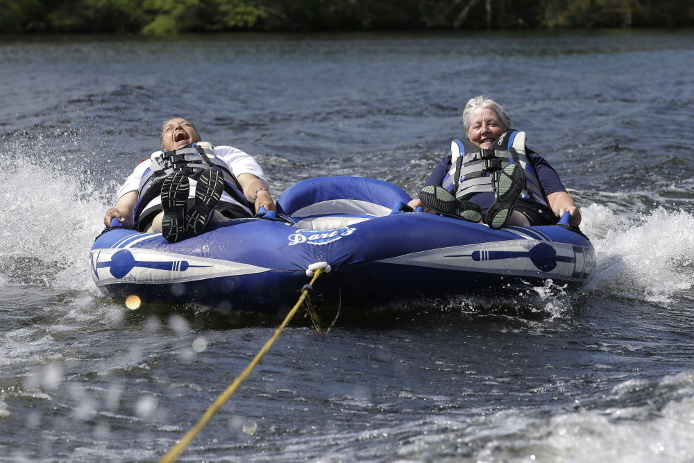 Navy veteran Raquel Ardin of North Hartland, Vt., left, who suffered a broken neck while serving in the Navy, laughs while riding an inflatable craft with her partner Lynda Deforge, right, also of North Hartland, during a rehabilitation clinic in Coventry, R.I.
