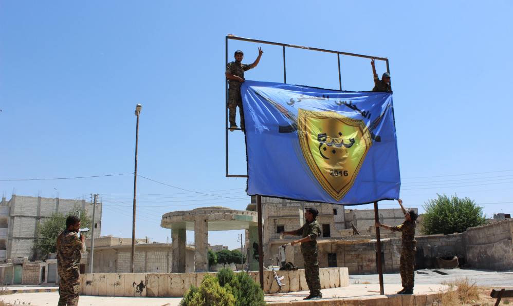 Kurdish-led Syria Democratic Forces raise their flag in the center of the town of Manbij after driving Islamic State militants out of the key Islamic State stronghold in Aleppo province in northern Syria following two months of heavy fighting.
