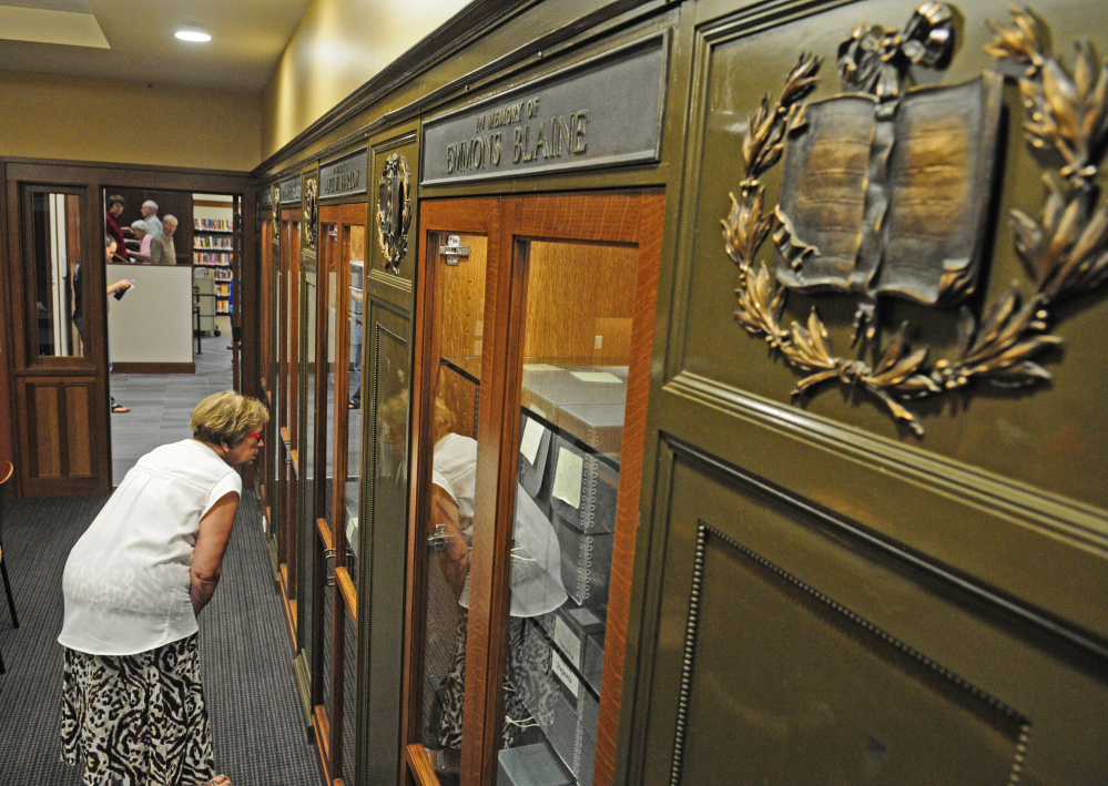City Councilor Anna Blodgett looks at a case in a board room Saturday at Lithgow Public Library in Augusta. The metal plaques from the ends of bookcases in the 1896 section of library are displayed in the small first-floor meeting room.