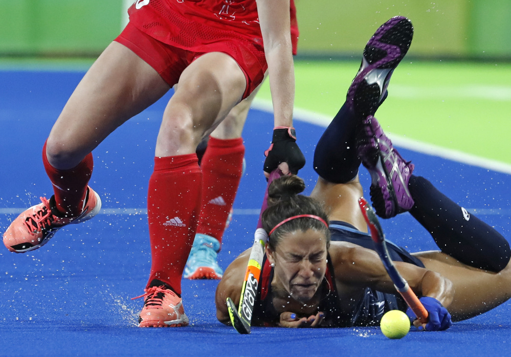Melissa Gonzalez of the U.S. falls while fighting for the ball with Britain's Nicola White during a field hockey preliminary-round match Saturday. The U.S. suffered its first loss of the tournament, 2-1.