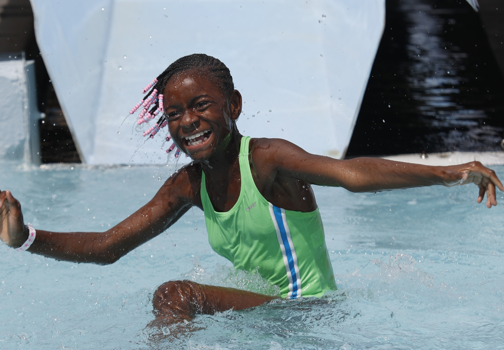 Malaysia White, 11, a Fresh Air Fund child from New York City, smiles after reaching the bottom of a water slide Sunday.