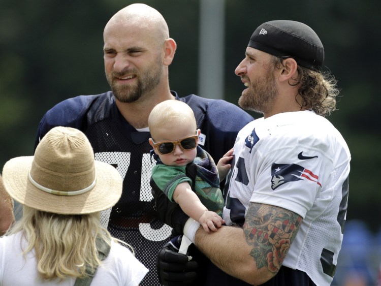 Defensive end Chris Long of the Patriots, right, holds his 5- month-old son, Waylon, while meeting his brother Kyle, a Bears offensive lineman. The teams are working out together.
