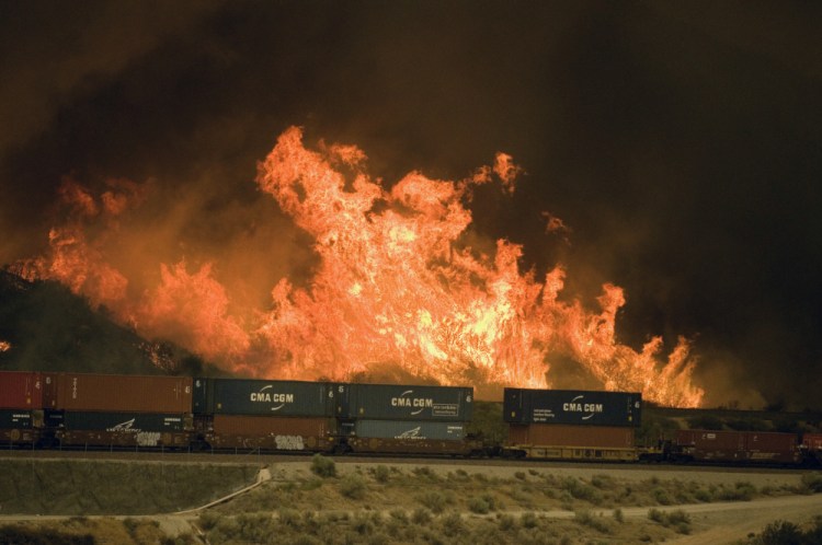 Flames erupt on a hillside alongside one of the main rail routes connecting Southern California with points north and east as a wildfire rages out of control in Cajon Pass north of Devore.