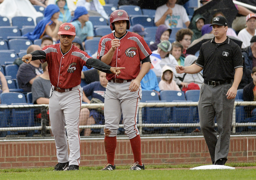 Altoona manager Joey Cora, left, gives instructions from the third base box during  Tuesday's game. On third base is Altoona's Christopher Diaz. 
