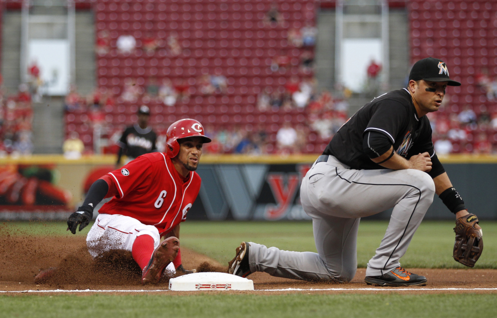 Cincinnati Reds' Billy Hamilton, left, slides into third with a steal as the ball gets away from Miami Marlins third baseman Martin Prado during the thrid inning of a baseball game Thursday, Aug. 18, 2016, in Cincinnati. (AP Photo/Gary Landers)