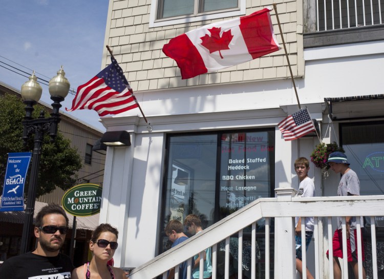 Canadian and American flags wave recently outside a restaurant in Old Orchard Beach. This coastal Maine town has long been a preferred destination for Canadian tourists, especially from Quebec.
