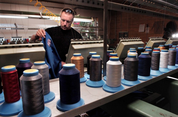 OriginUSA employee Peter White prepares to embroider a gi garment at the company manufacturing facility in Industry.