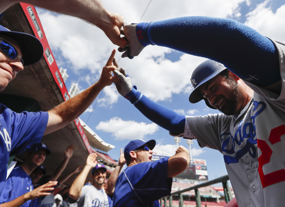 The Dodgers' Adrian Gonzalez, right, celebrates in the dugout after hitting a three-run home run off Reds relief pitcher Jumbo Diaz in the seventh inning of an 18-9 win at Cincinnati on Monday. Gonzalez hit three home runs in the game, driving in a career-high eight runs.