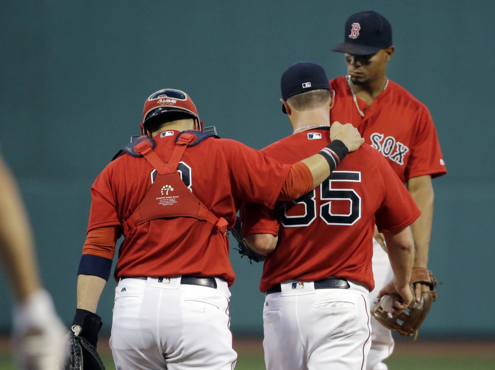 Red Sox catcher Sandy Leon puts his arm around starting pitcher Steven Wright as shortstop Xander Bogaerts approaches for a mound conference in the first inning Friday night against the Kansas City Royals at Fenway Park. Wright gave up five runs in the first inning.