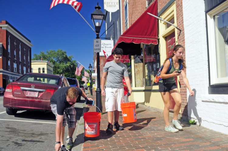 From left, Phillip Jones, Luke Robinson and Clarrissa Lettre pick up cigarette butts and other trash Saturday as they play Pokemon Go on Water Street in Hallowell.