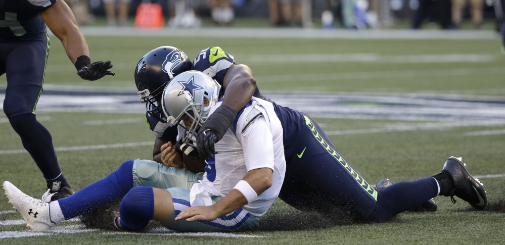 Cowboys quarterback Tony Romo is tackled by Seattle defensive end Cliff Avril in a preseason game on Thursday. Romo suffered a broken bone in his back on the play.