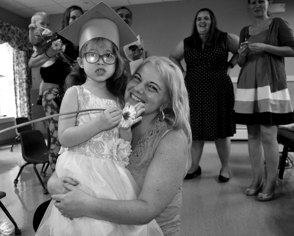 Fraser-Ford Child Development Center ed tech Melissa Chrusicel hugs her student Natalie moments after the conclusion of graduation ceremonies, surrounded by parents and staff at Waban's Wormwood Center.