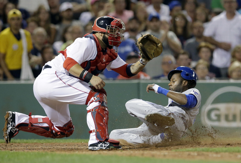 Kansas City's Lorenzo Cain slides safely at home as Red Sox's Sandy Leon waits for the ball in the sixth inning Sunday in Boston.