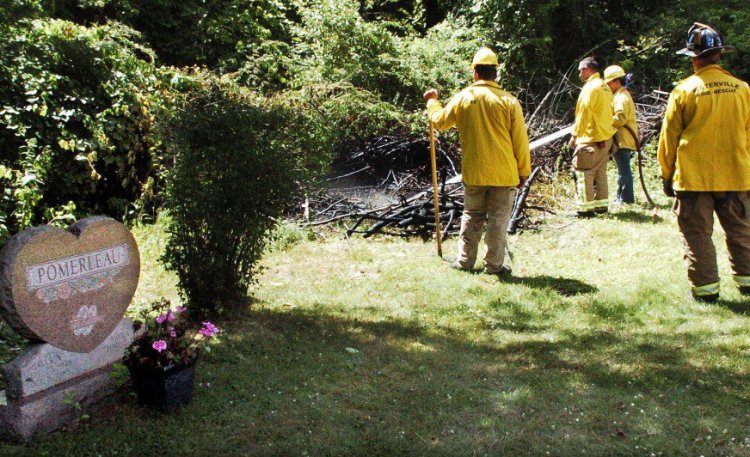 Waterville firefighters extinguish a fire in some brush near gravesites at the St. Francis Catholic Cemetery in Waterville on July 21. Photo by David Leaming / Morning Sentinel