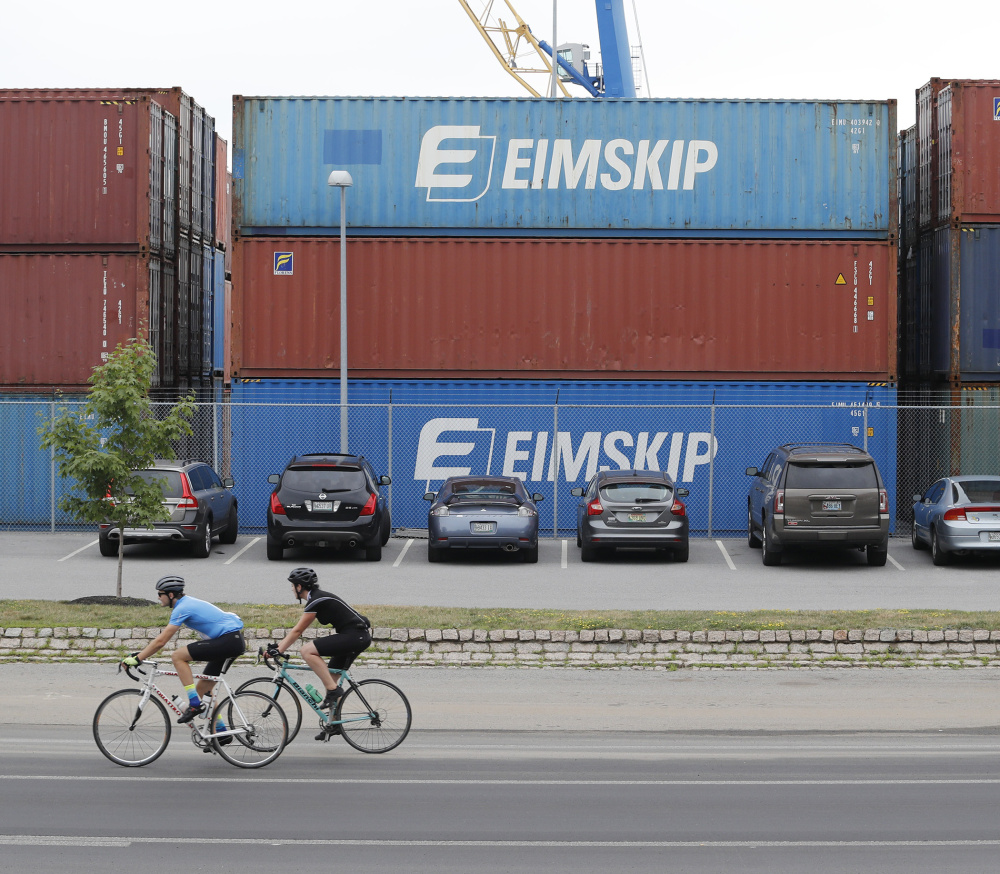 Cyclists pass shipping containers Monday at the International Marine Terminal. Iceland's Eimskip uses some converted containers as year-round office space at the terminal.