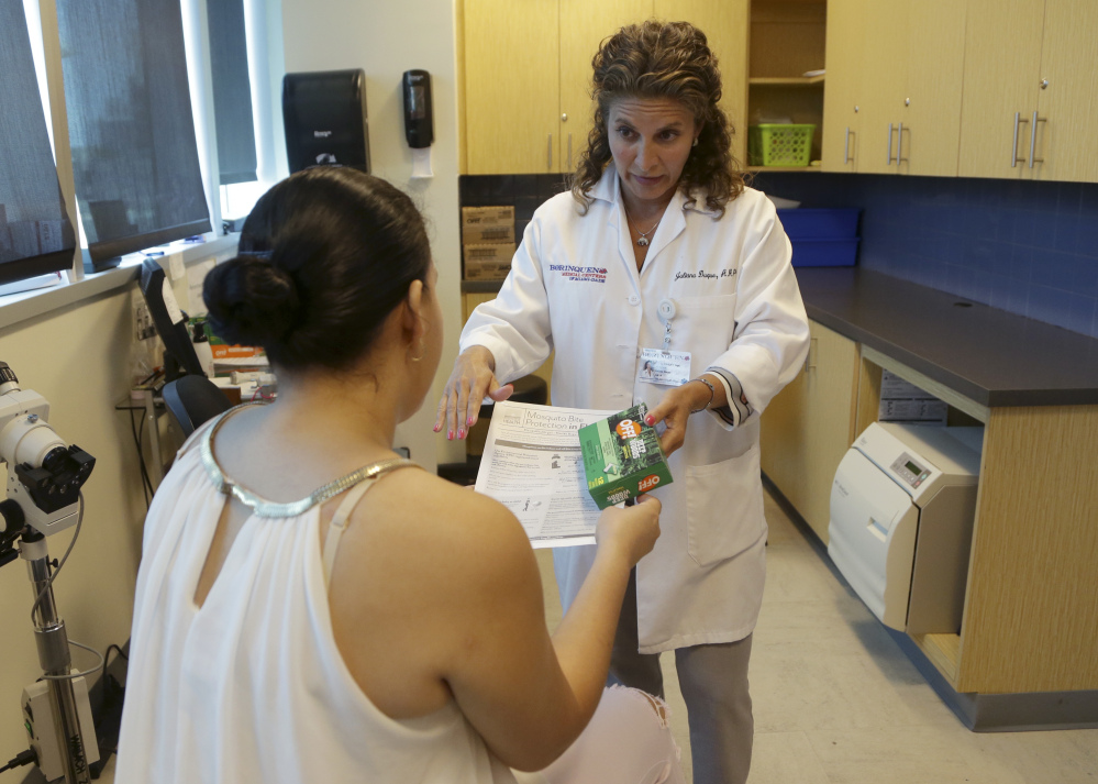 Nurse practitioner Juliana Duque, right, gives a patient, who is in her first trimester of pregnancy insecticide and and information about mosquito protection at the Borinquen Medical Center, Tuesday, Aug. 2, 2016 in Miami. The CDC has advised pregnant women to avoid travel to the nearby neighborhood of Wynwood where mosquitoes are apparently transmitting Zika directly to humans. The patient also had a test for the Zika virus following her exam.