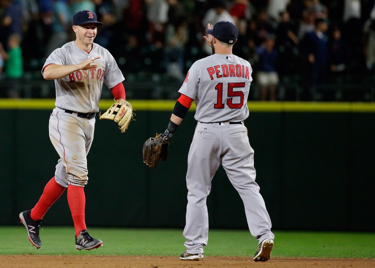 Boston Red Sox outfielder Brock Holt, left, greets second baseman Dustin Pedroia (15) at the end of Thursday's game against the Seattle Mariners in Seattle. The Red Sox beat the Mariners 3-2 in 11 innings. 