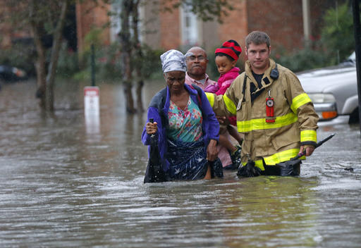 A member of the St. George Fire Department assists residents as they wade through floodwaters from heavy rains in Baton Rouge, La., on Friday. 
AP Photo/Gerald Herbert