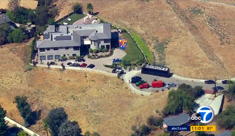 This image from aerial video provided by KABC-TV shows the home of entertainer Chris Brown with a police vehicle outside Tuesday. Authorities waited for a search warrant outside Brown's Los Angeles home Tuesday after a getting a woman's call for help, officials said.   KABC-TV via Associated Press
