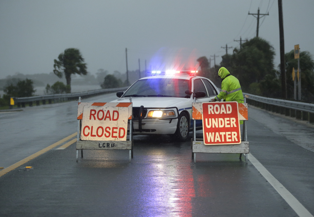 Police block the road to Cedar Key, Fla., as Hurricane Hermine nears the Florida coast Thursday. Rough surf smashed against docks and boathouses, and people braced for the state's first direct hit from a hurricane in over a decade.