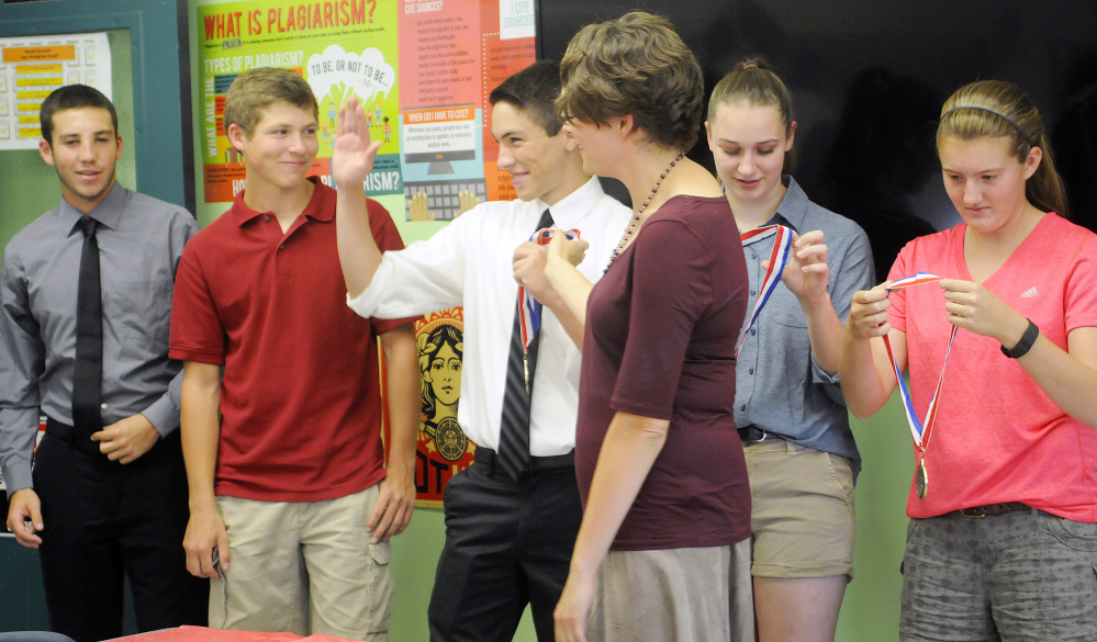 Monmouth Academy juniors receive medals Thursday from teacher Jocelyn Gray, center front, for their project on Acadian deportation. At rear from left are Devon Poisson, Dylan Goff, Cody Roy, Maddie Amero and Abbey Allen.
