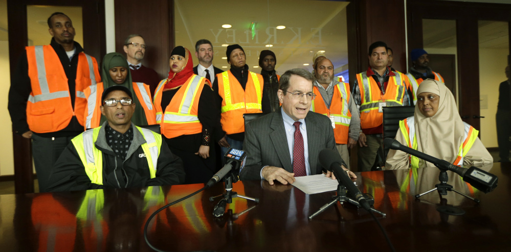 In a photo from earlier this year, attorney Duncan Turner, middle, is backed by workers at Seattle-Tacoma International Airport who sued their employers over the nation's first $15 minimum wage, which they said they did not receive.