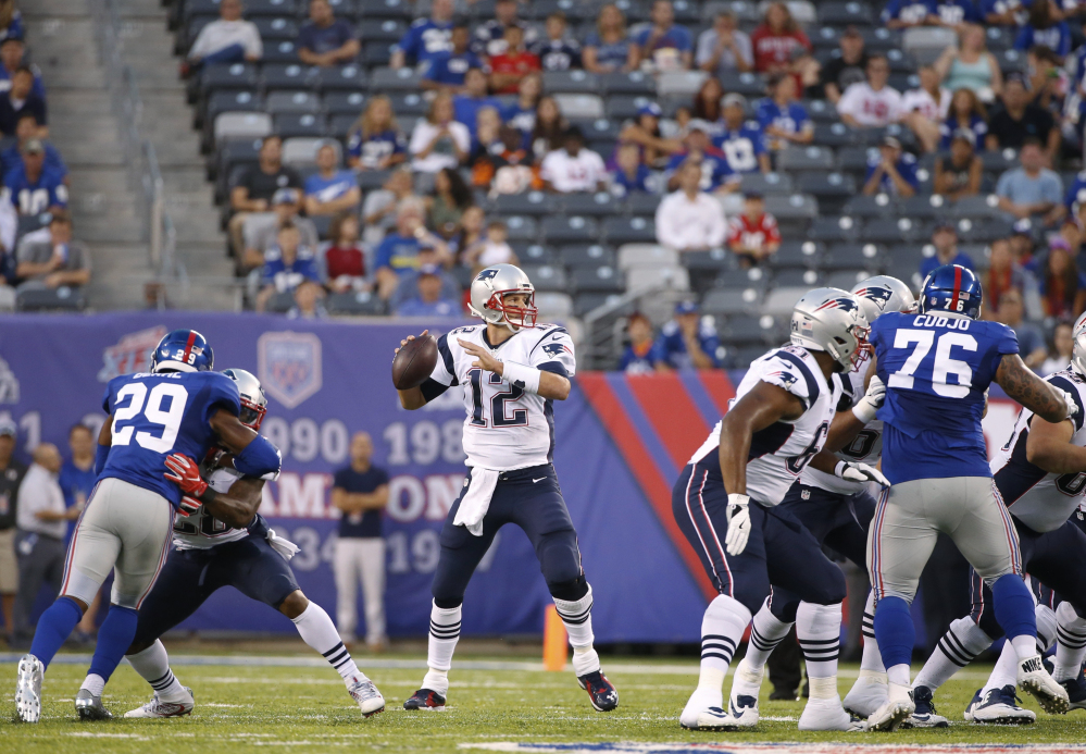 Patriots quarterback Tom Brady looks to pass as New York Giants strong safety Nat Berhe, 29, and Jermelle Cudjo rush during the first half Thursday in East Rutherford, N.J. Brady was intercepted on the play.