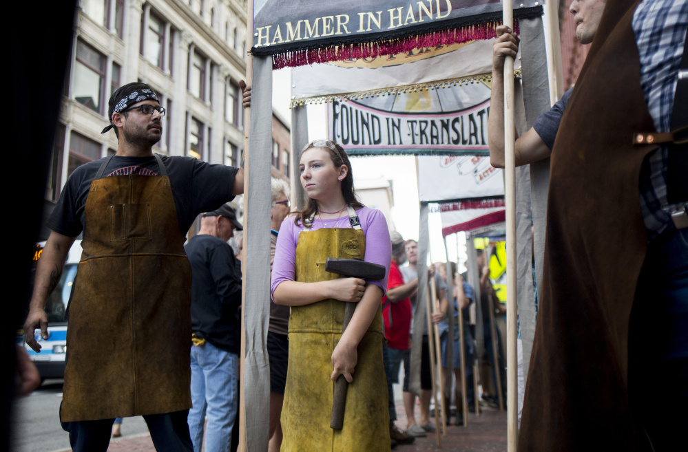 Lucas Damen, a part-time blacksmith, and Fuchsia Harmon, 11, who is taking blacksmithing classes, hold the banner for their trade before the Working People's Parade in Portland on Friday, an event that was inspired by a local history of labor parades.